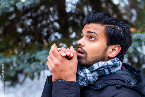 indian man enjoying snowflakes falling from upwards in forest photo