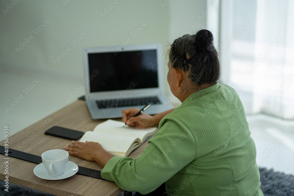 Asian senior retired business woman working at home with Laptop computer in new normal Asian senior retired business woman working at home with Laptop computer in new normal
