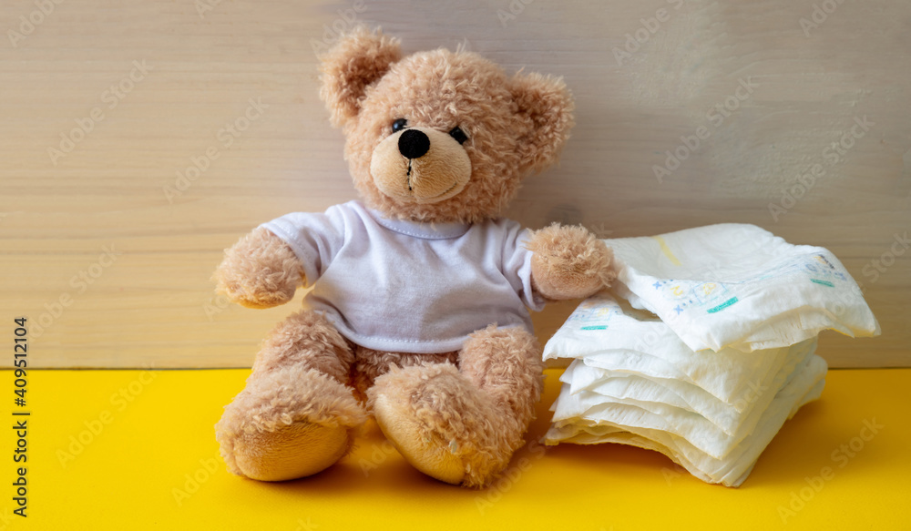 Baby diapers and teddy on yellow color floor