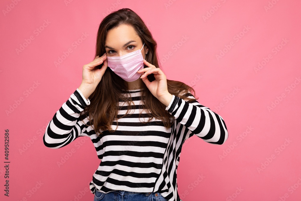 Young woman wearing an anti virus protection mask to prevent others from corona COVID-19 and SARS cov 2 infection isolated over pink background Young woman wearing an anti virus protection mask to prevent others from corona COVID-19 and SARS cov 2 infection isolated over pink background