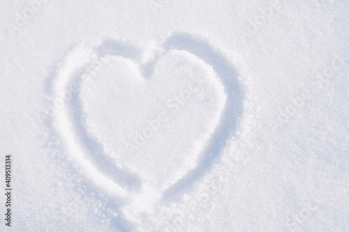 Drawing in the shape of a heart on white snow .