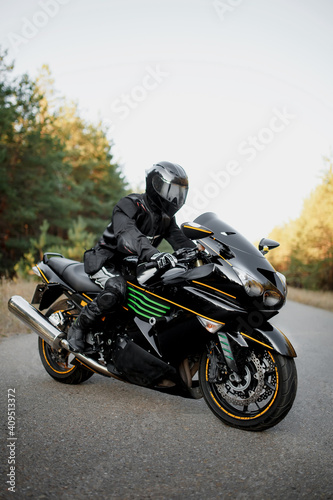 Rider on a motorbike driving at sunset - space for your text, biker and motorbike ready to ride