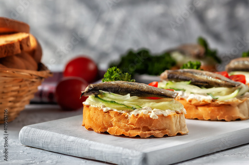 Smoked sprat sandwich - fish, fresh cucumber and tomato. Sprat sandwiches on toasted slices of bread
