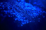 Blue glitter texture. Sequins scattered on a black background. Shimmering effect. Bokeh.