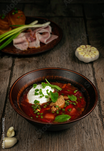 Ukrainian borscht on a wooden table with bacon and garlic