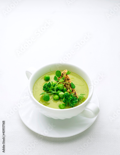 Green pea soup in a soup bowl on a white background