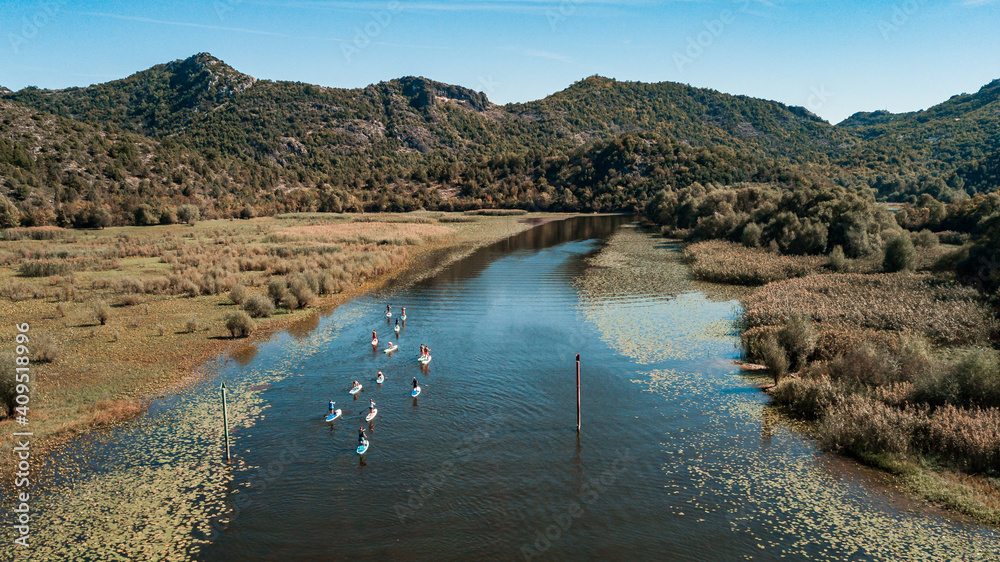 A group of tourists on SUP stand up paddle boards in Rijeka Crnojevica river in Skadar Lake National Park Montenegro