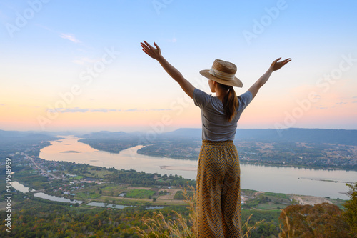 Asian woman enjoying high angle view of Mekong river with open hands standing on the cliff in Nongkhai, Thailand