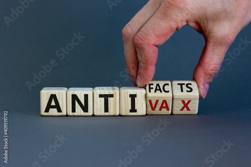 Anti-facts or anti-vax symbol. Doctor turns a cube, changes words 'anti-vax' to 'anti-facts'. Beautiful grey background. Copy space. Business, medical covid-19 anti-facts or anti-vax concept. photo