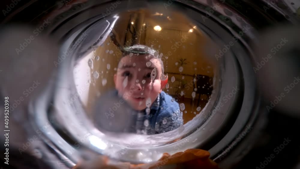 A child looks in surprise into a working washing machine