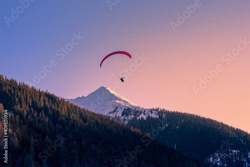 Vibrant Sunset Paragliding Over Majestic Swiss Alps
Paraglider above Swiss alps mountain peak while sunset.  photo