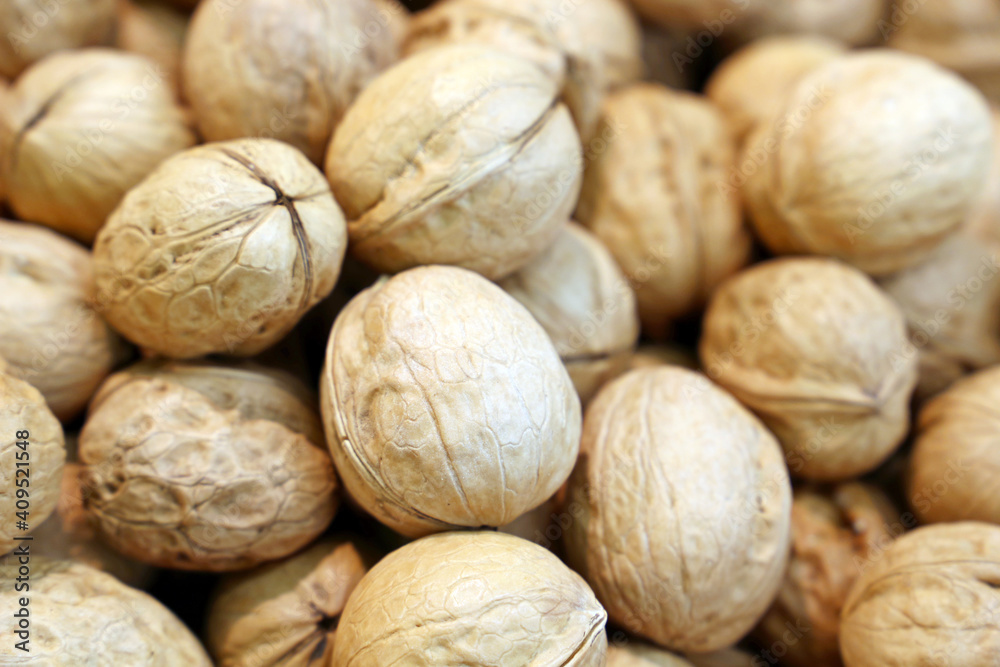 Whole walnuts heap for background. Dry nuts in shells, brain food