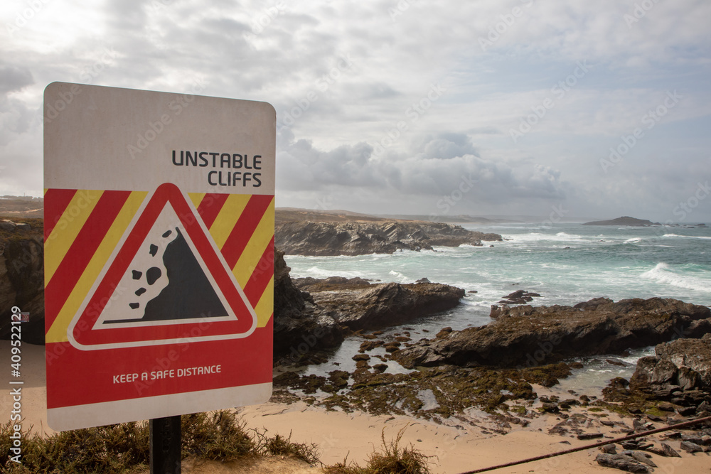 Coastline with warning cliff sign, Porto Covo, Sines, Portugal.