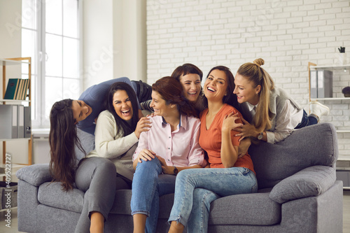 Group of happy friends having fun and enjoying free time together. Carefree young women sitting on sofa at home  laughing and fooling around. Concept of friendship  sharing happiness  mutual support