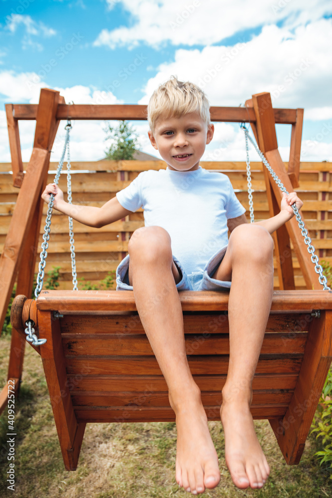 Kid toddler boy swinging on a playground swing in the backyard a Kid toddler boy swinging on a playground swing in the backyard a
