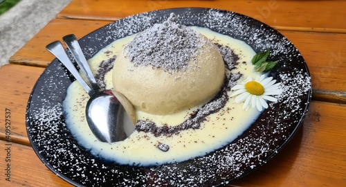 Germknödel - sweet Austrian dumpling filled with jam served with vanilla sauce, poppy seeds and butter