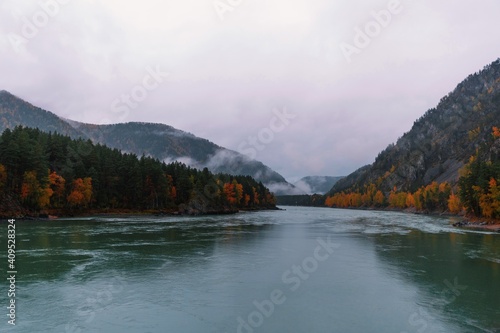 Beautiful autumn landscape of forest mountains in fog after rain. The Great Altai Mountains are the best place for recreation and tourism. The Katun River flows at the foot of the mountains.