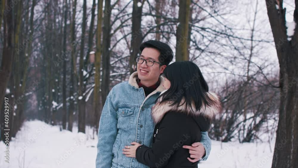 Happy young asian couple kissing under the tree covered in snow. Winter season love and affection. Valentines day. High quality 4k footage Happy young asian couple kissing under the tree covered in snow. Winter season love and affection. Valentines day. High quality 4k footage