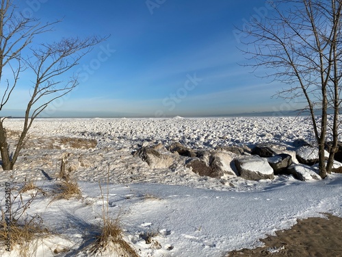 Frozen shoreline of Lake Michigan after a winter storm. Snow drifts formed at the water's edge and ice balls formed from the rolling waves. Taken at Gillson Beach in Wilmette, Illinois.