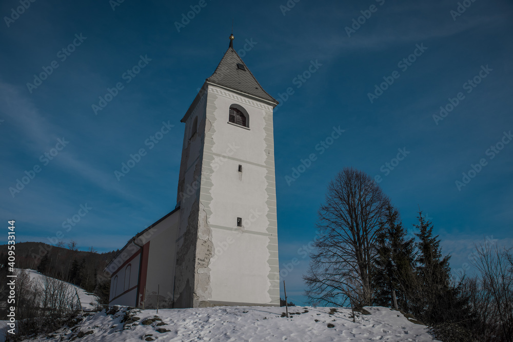 Panoramic view of Catholic church of Holy Ahacij in Kalise, Slovenia on a sunny winter day with some snow visible. Cold but warm feeling.