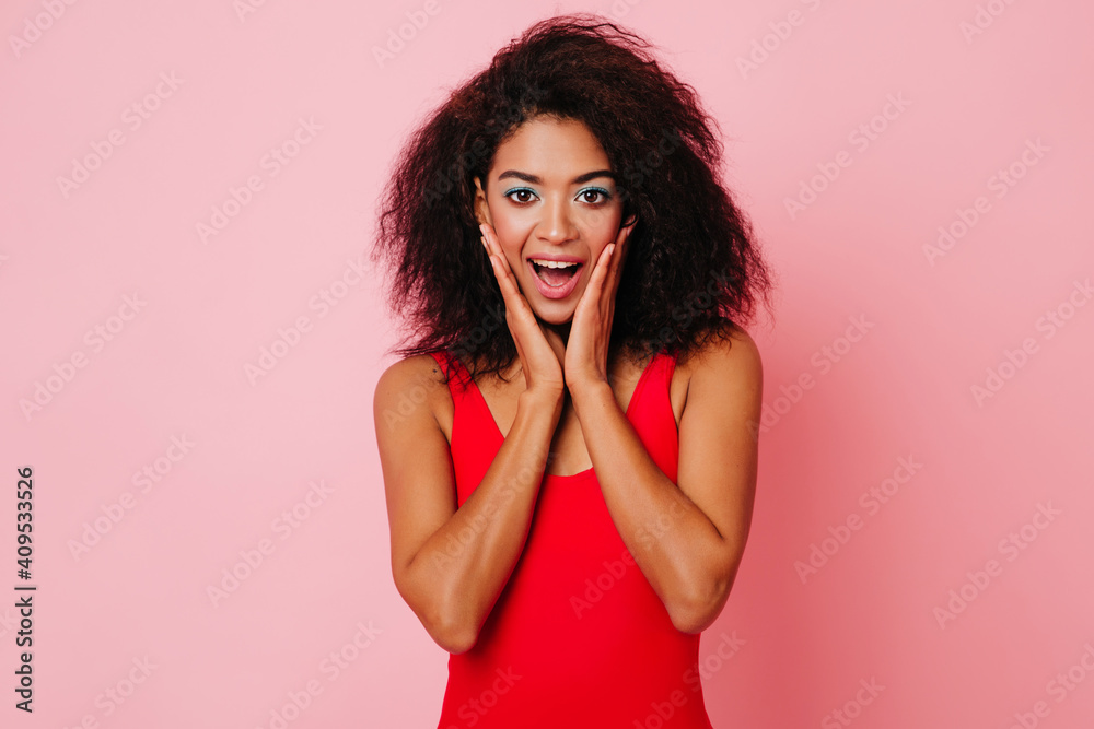 African girl in red clothes expressing amazement. Studio shot of emotional woman isolated on pink background.