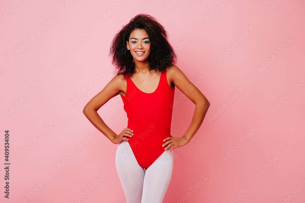 Inspired fitness girl standing in confident pose. Graceful african young woman posing in sport bodysuit. Inspired fitness girl standing in confident pose. Graceful african young woman posing in sport bodysuit.