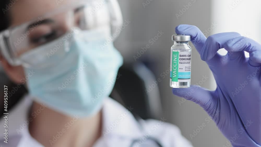 Female scientist holding ampoule in hand, new medication developing, vaccination. Vaccine dose close up. Presentation of vaccine from COVID-19 coronavirus. Global pandemic finishes. Health concept. Female scientist holding ampoule in hand, new medication developing, vaccination. Vaccine dose close up. Presentation of vaccine from COVID-19 coronavirus. Global pandemic finishes. Health concept.