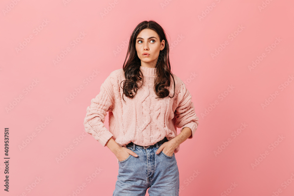 Portrait of woman in knitted sweater and blue jeans on isolated background. Pretty girl cute bites her lip Portrait of woman in knitted sweater and blue jeans on isolated background. Pretty girl cute bites her lip