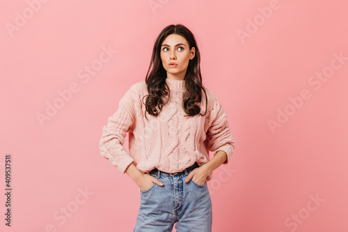 Portrait of woman in knitted sweater and blue jeans on isolated background. Pretty girl cute bites her lip © Look!