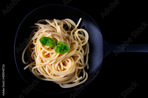 Italian spaghetti with basil leaves cooked in a colander