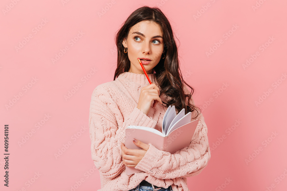 Dark-haired woman in knitted sweater looks up thoughtfully. Lady thinks what to write in new book Dark-haired woman in knitted sweater looks up thoughtfully. Lady thinks what to write in new book