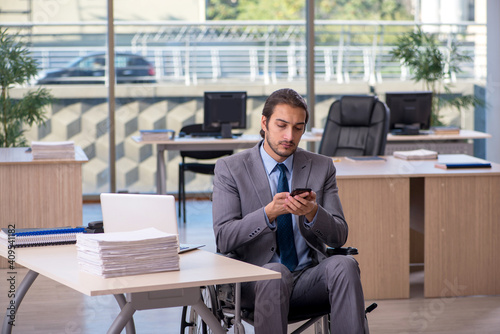 Young male employee in wheel-chair working in the office