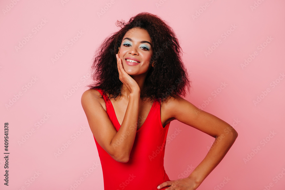 Curly young woman laughing on pink background. Studio shot of african girl with wavy hair. Curly young woman laughing on pink background. Studio shot of african girl with wavy hair.