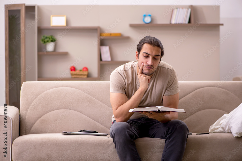Young male student reading book at home Young male student reading book at home