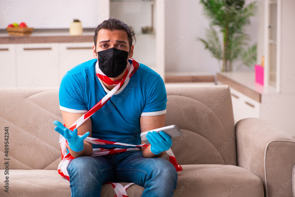 Obraz premium Young man watching tv at home in pandemic concept