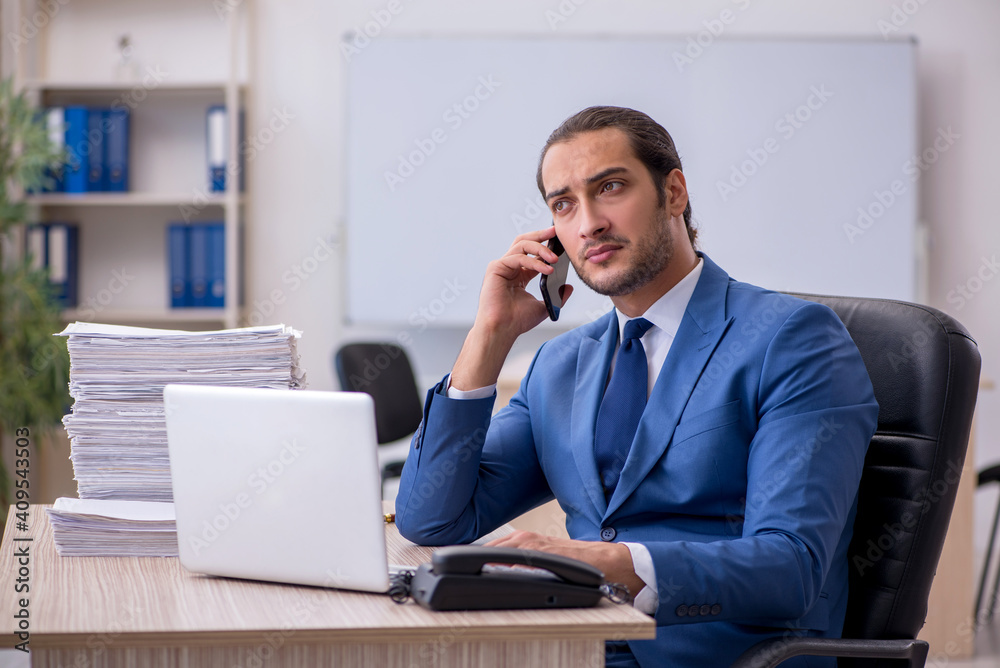 Young male employee and too much work in the office Young male employee and too much work in the office
