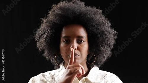 finger on lips closeup portrait of beautiful black woman photo