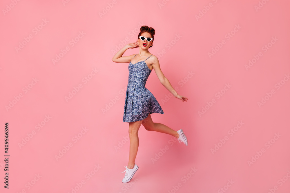Full length view of inspired lady in blue dress. Relaxed pinup girl dancing on pink background.