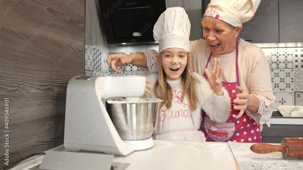 Grandmother and grandchild are enthusiastic during mixing a dough for doughnuts Grandmother and grandchild are enthusiastic during mixing a dough for doughnuts