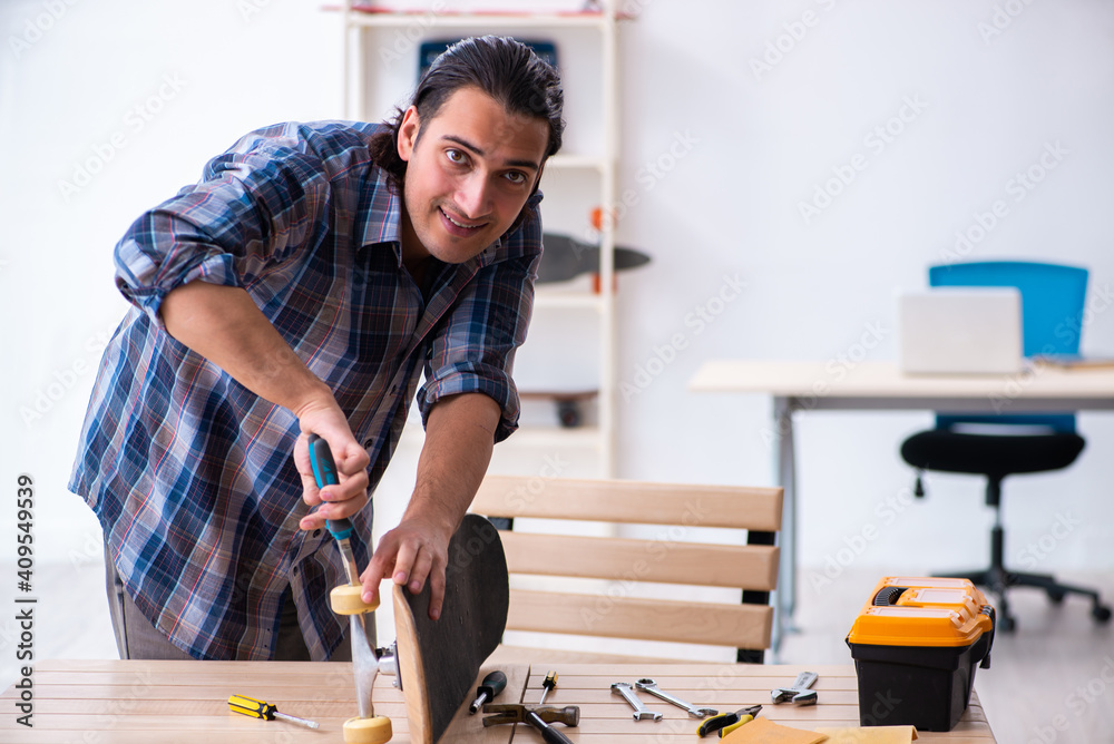 Young man repairing skateboard at workshop Young man repairing skateboard at workshop