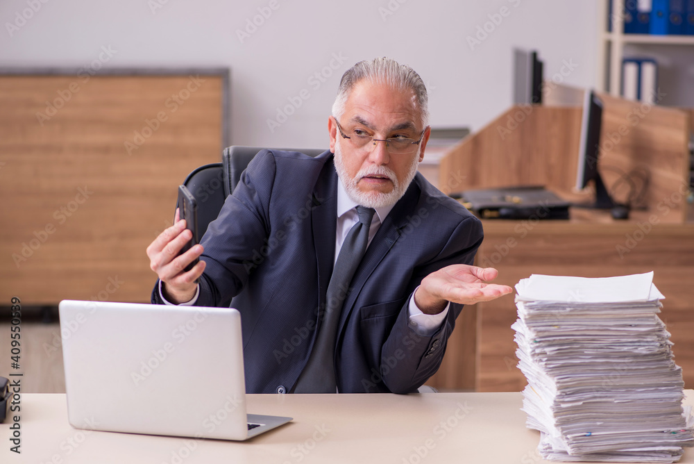 Old male employee unhappy with excessive work in the office Old male employee unhappy with excessive work in the office