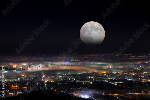 満月が夜霧に包まれた街を照らす