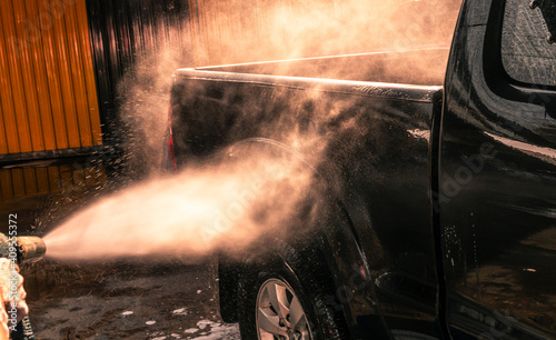 Close up photo of a man hands washes his car with a large head of water from a karcher on open air. Cleaning and disinfection. Security measures during the epidemic