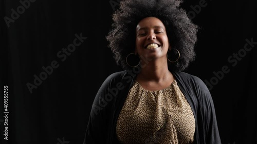 studio portrait of beautiful black woman laughing in front of black backdrop photo