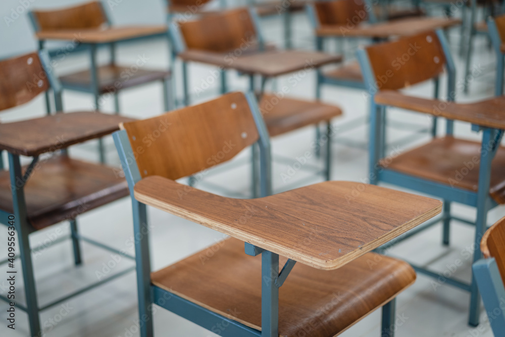 Empty university classroom with many wooden chairs. Wooden chairs well arranged in college classroom. Empty classroom with vintage tone wooden chairs. Back to school concept.