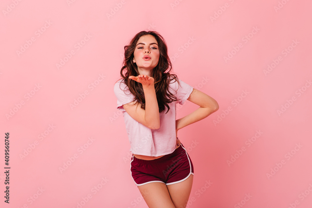Charming woman in light T-shirt and dark shorts blowing kiss on isolated background Charming woman in light T-shirt and dark shorts blowing kiss on isolated background
