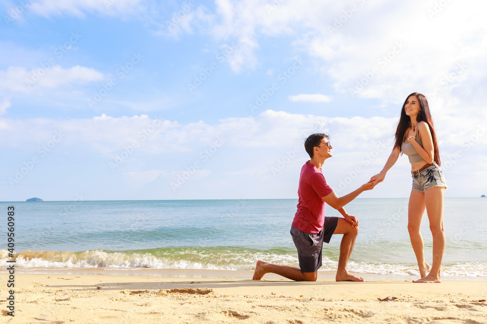 A Male making a wedding porposal on the beach.