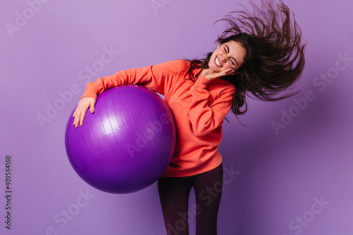 Nice girl shakes her head vigorously while holding fitball. Emotional joyful woman doing aerobics