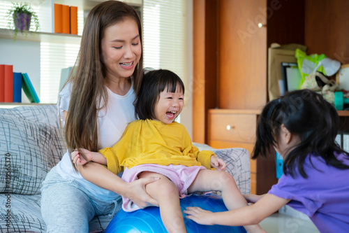 A mother, two Asian daughters, happily playing at home, mother and daughter smiles