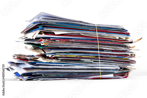 Junk mail stacked high of unpaid bills closeup white isolated background.